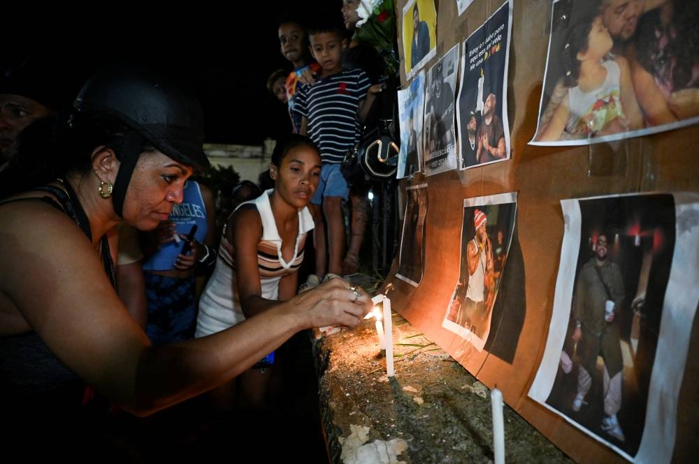 Los cubanos encienden velas junto a fotografías del fallecido cantante de reguetón José Manuel Carbajal 039El Taiger039. / AFP,image_description: