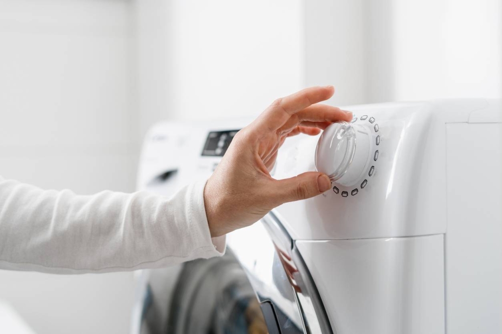 El 27.4  de la población salvadoreña tiene lavadora, según la EHPM. /DEM,image_description:female hand choose mode with knob on washing machine indoors