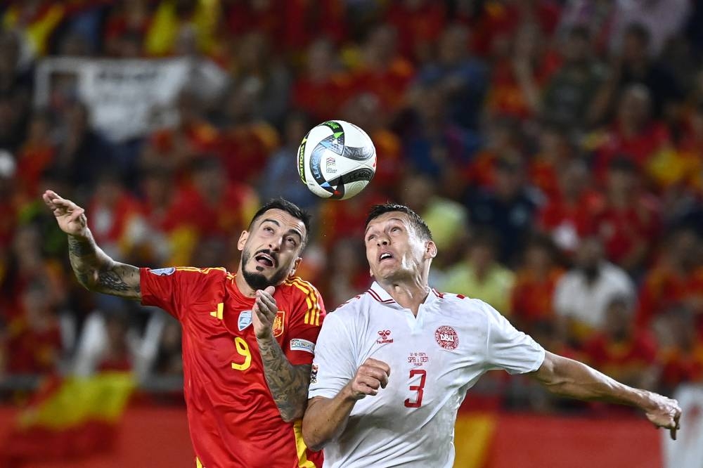 El español Joselu disputa la pelota con Jannik Vestergaard, de Dinamarca. / AFP,image_description: