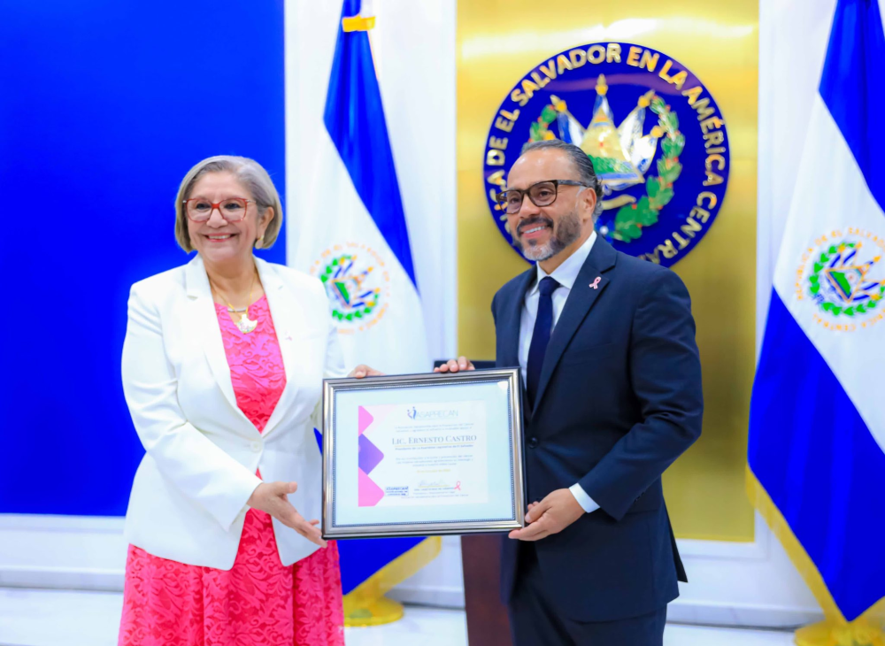 La presidenta de la Asociación Salvadoreña para la Prevención del Cáncer Asaprecan, Lisseth Guadalupe Ruiz de Campos, entregó el reconocimiento a Ernesto Castro, presidente de Asamblea Legislativa. / AsambleaSV.,image_description: