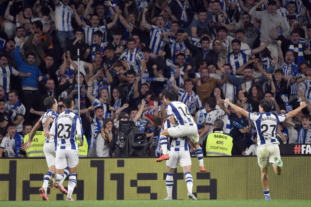 Los jugadores de la Real Sociedad celebran el gol del empate marcado por el centrocampista croata 24 Luka Susic durante el partido de fútbol de la liga española entre la Real Sociedad y el Club Atlético de Madrid en el estadio de Anoeta en San Sebastián el 6 de octubre de 2024. / AFP,image_description: