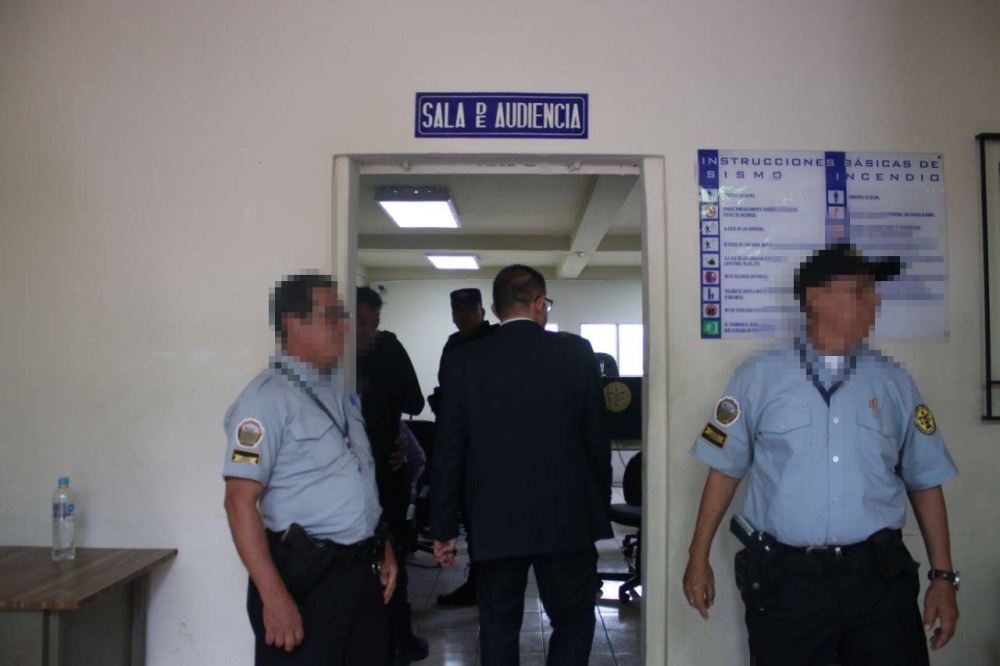 Custodios afuera de la sala de audiencia del Tribunal de Sentencia de Sensuntepeque donde se da el fallo del caso Santa Marta. / Lisbeth Ayala.,image_description: