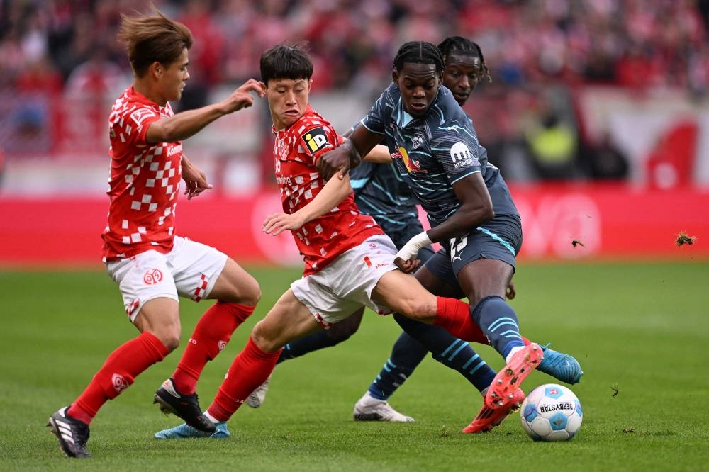 Kaishu Sano y Jaesung Lee lucha contra Castello Lukeba. / AFP,image_description:Football: Bundesliga  day 7: Mainz 05 v RB Leipzig