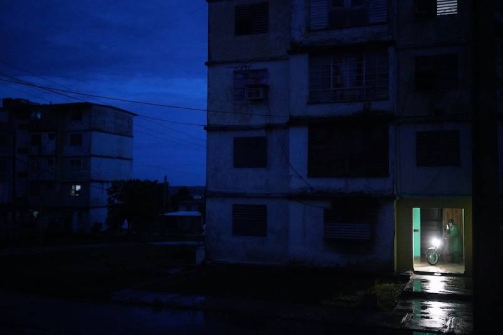 Un motociclista es visto en el vestíbulo de un edificio durante un apagón nacional causado por una falla en la red en Matanzas, Cuba. El apagón afecta a los 10 millones de cubanos./ AFP,image_description: