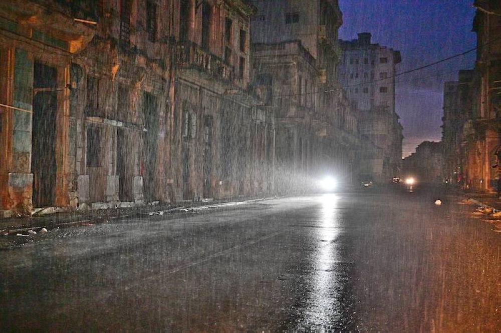 Una motocicleta ilumina una calle bajo una lluvia torrencial durante un apagón nacional provocado por un fallo en la red eléctrica en La Habana, el 19 de octubre de 2024./ AFP