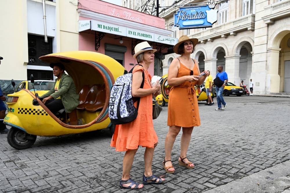 Una pareja de turistas camina por una calle de La Habana el 21 de octubre de 2024. En plena su peor crisis económica en tres décadas, la isla recibió 2,4 millones de turistas en 2023, el 68,5 de los 3,5 millones que tenía previstos, y muy poco del récord de 4,7 millones que llegaron al país en 2018 a raíz del histórico acercamiento con Estados Unidos/ Yamil Lage AFP.,image_description: