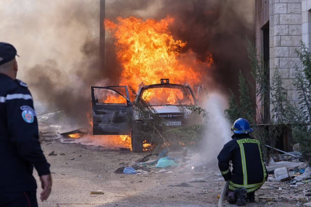 Un bombero palestino apaga las llamas que envuelven un automóvil tras una incursión israelí en Tulkarem, en el norte de la Cisjordania ocupada, el 26 de octubre de 2024. Foto de JAAFAR ASHTIYEH / AFP,image_description: