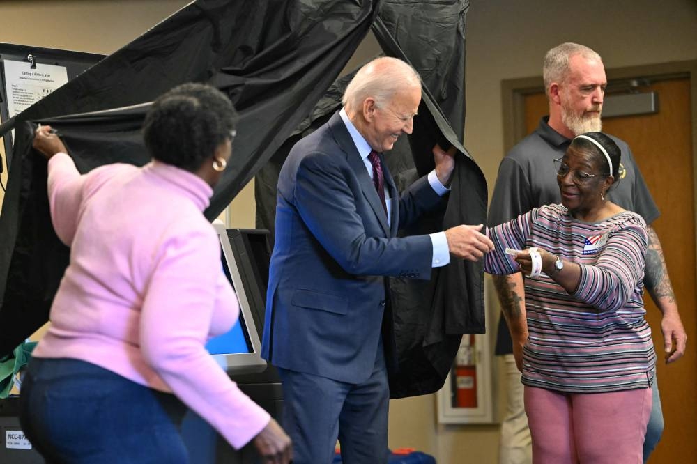 El presidente de Estados Unidos, Joe Biden, recibe una calcomanía de Yo voté cuando sale de la cabina después de emitir su voto anticipado en las elecciones generales de 2024 en New Castle, Delaware, el 28 de octubre de 2024. /AFP,image_description: