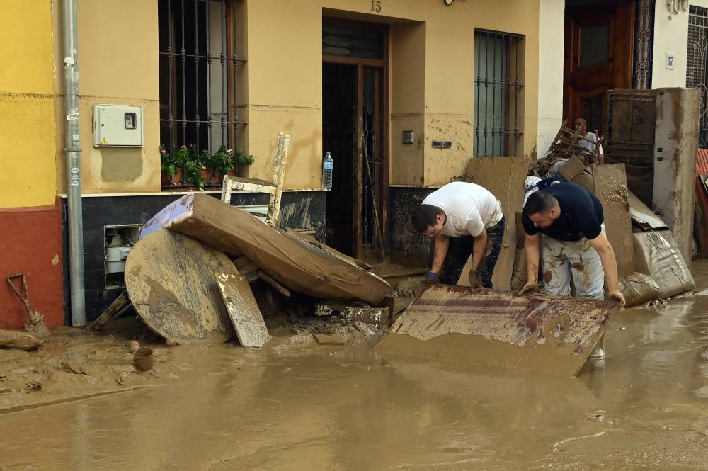 Los residentes intentan limpiar sus casas mientras la calle está cubierta de barro este 31 de octubre de 2024 después de que inundaciones repentinas afectaran a La Torre, en Valencia, al Este de España. /AFP ,image_description: