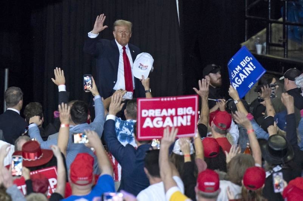 El expresidente estadounidense y candidato presidencial republicano Donald Trump saluda a sus simpatizantes mientras camina hacia el escenario durante un mitin de campaña en el Centro Cívico de Salem en Salem, Virginia./AFP,image_description: