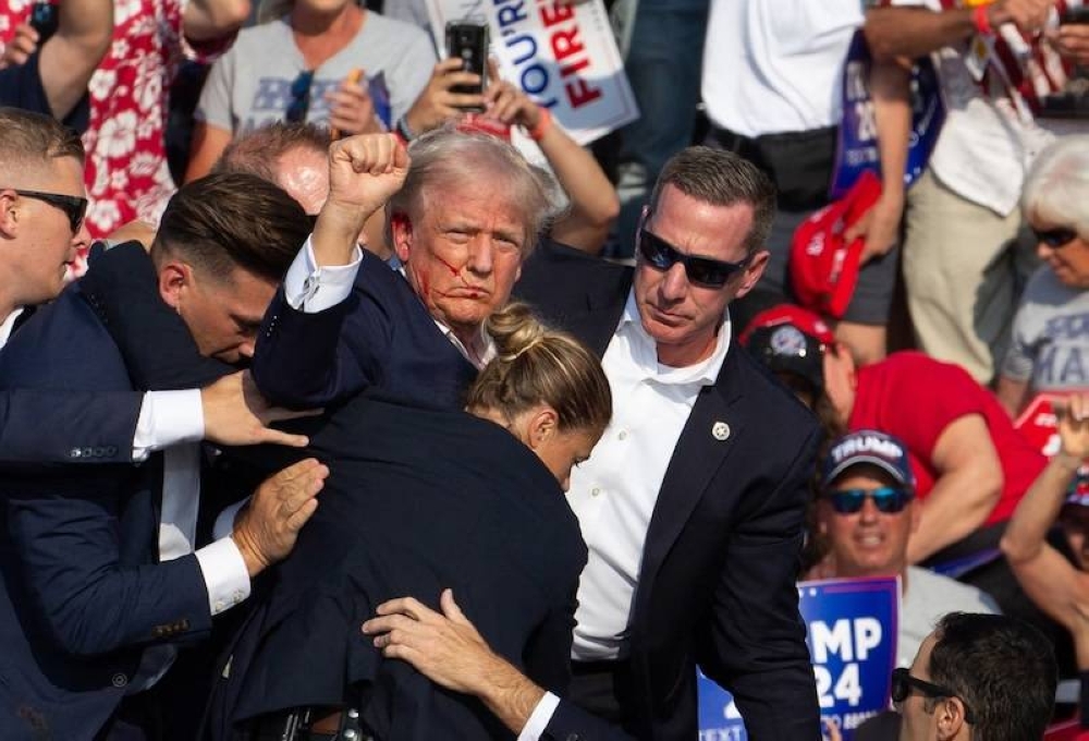 El expresidente Donald Trump es visto con su rostro cubierto de sangre al ser evacuado por agentes del Servicio Secreto tras el atentado en su contra en Butler, Pensilvania el 13 de julio de 2024./AFP