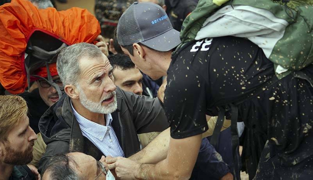 El rey Felipe VI de España habla con una persona mientras los residentes enojados lo abuchean durante su visita a Paiporta, en la región de Valencia. /AFP,image_description: