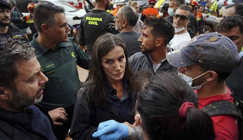 La reina Letizia de España, con manchas de barro en la cara, escucha a un residente de la ciudad durante la visita de la pareja real española a Paiporta. /AFP