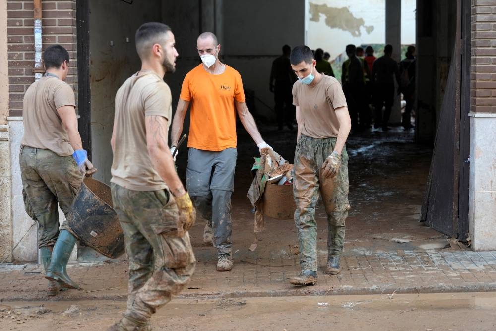 Soldados españoles con máscaras retiran escombros en Aldaia, al oeste de Valencia, en el este de España, el 5 de noviembre de 2024, tras unas devastadoras inundaciones. /Cesar Manso / AFP,image_description: