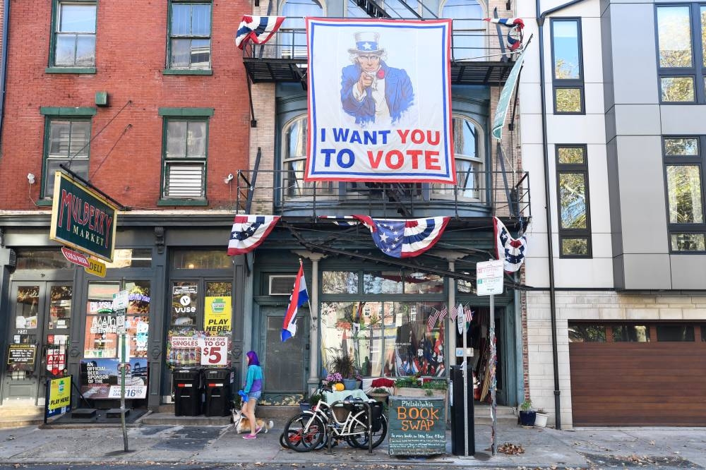 Un cartel que anima a la gente a votar cuelga de la fachada de un edificio en el centro de Filadelfia, Pensilvania, el día de las elecciones, el 5 de noviembre de 2024. Foto de MATTHEW HATCHER / AFP,image_description: