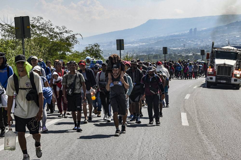 Migrantes de diferentes nacionalidades caminan hacia Estados Unidos en una caravana por una carretera en Tuxtla Gutiérrez, estado de Chiapas, México. /AFP,image_description: