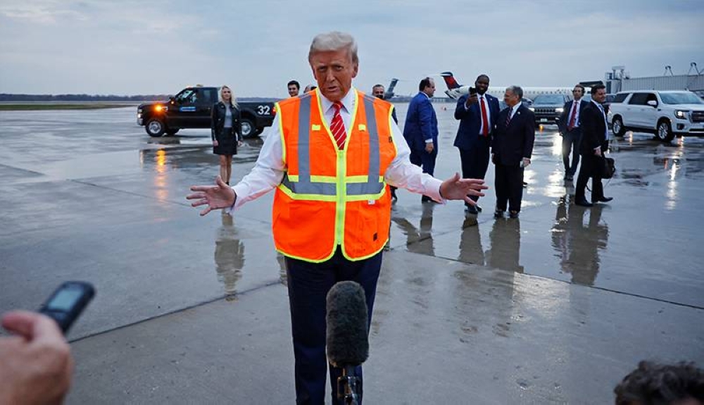 Donald Trump, habla con los periodistas mientras usa un chaleco de seguridad en la pista del Aeropuerto Internacional Austin Straubel de Green Bay el 30 de octubre de 2024 en Green Bay, Wisconsin. /AFP,image_description: