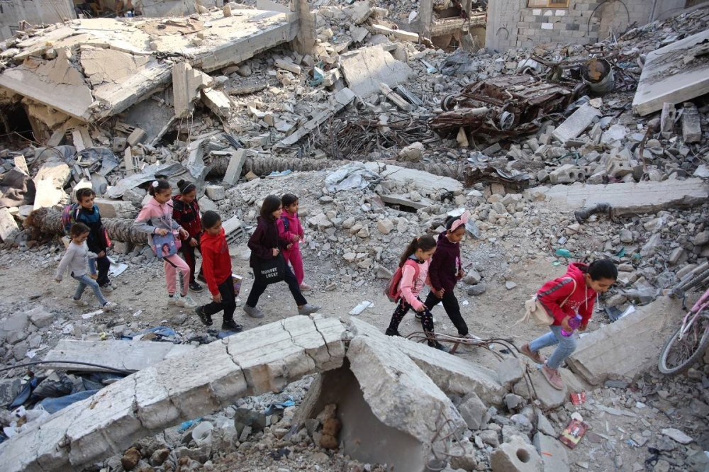 Niñas palestinas caminan entre los edificios destruidos luego de un bombardeo israelí en Gana el 9 de noviembre, en medio del conflicto en Gana entre Israel y el grupo Hamás. / AFP.,image_description: