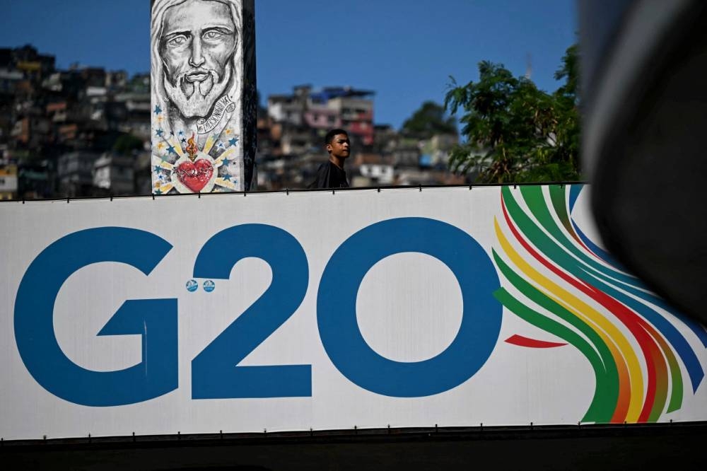 Una pancarta de la Cumbre del G20 se exhibe en un puente peatonal frente a la favela Rocinha, zona sur de Río de Janeiro, Brasil, el 6 de noviembre de 2024. La Cumbre será el 18 y 19 de noviembre. / AFP.,image_description: