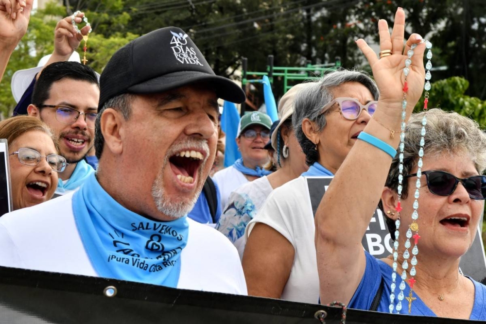 Católicos costarricenses gritan consignas en una marcha rumbo a la Corte Interamericana de Derechos Humanos CIDH contra el aborto, en San José, Costa Rica, el 10 de noviembre de 2024. / AFP.,image_description: