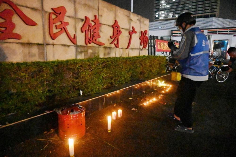 Un hombre mira las velas que quedaron afuera del Centro Deportivo de Zhuhai, un día después de que un automóvil se estrellara contra el lugar y matara a docenas de personas en Zhuhai, en la provincia de Guangdong, en el sur de China, el 12 de noviembre de 2024./ AFP,image_description: