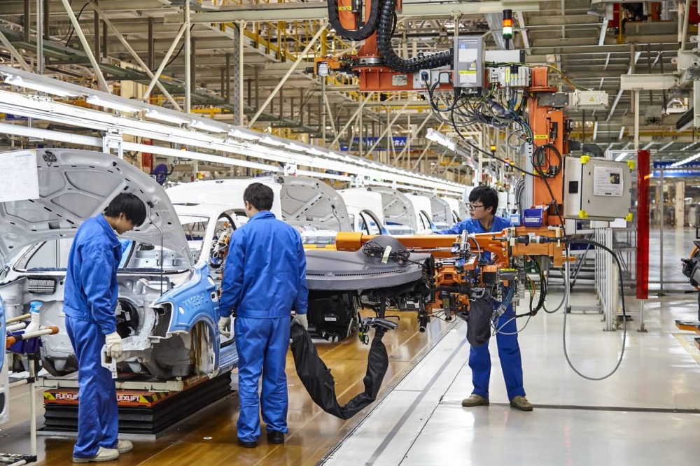 China es el mayor ofertante de carros en El Salvador con 14 marcas, aunque el volumen de venta se concentra con fabricantes de Japón y Corea. /DEM,image_description:Workers who install and install cars on the Shanghai Volkswagen factory assembly line are busy.