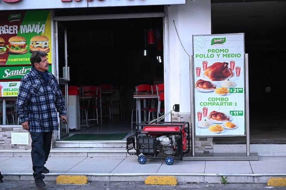 Un hombre camina junto a un generador durante un apagón en Quito, Ecuador. El gobierno ecuatoriano ordenó cortes de energía de hasta 12 horas diarias en noviembre, pero si las lluvias no caen para llenar los embalses, se endurecería el racionamiento. / AFP