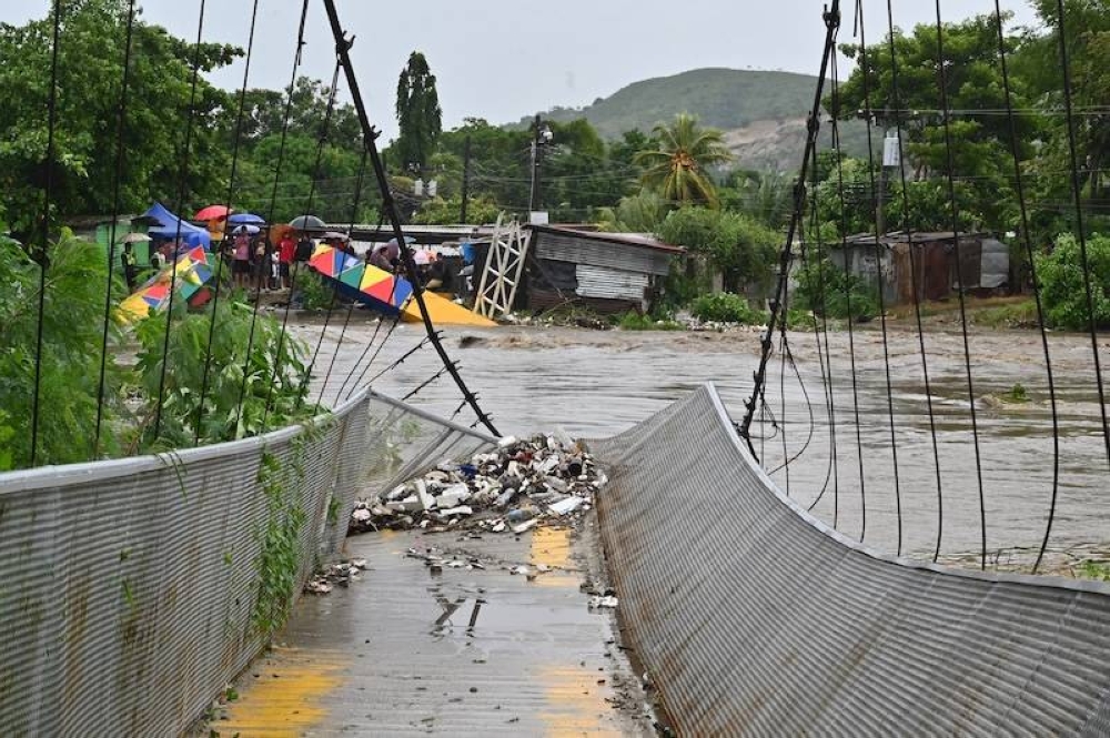 Vista de un puente que colapsó por la crecida del río Bermejo en San Pedro Sula, Honduras, debido a las fuertes lluvias que dejó la tormenta tropical Sara el sábado 16 de noviembre./AFP ,image_description: