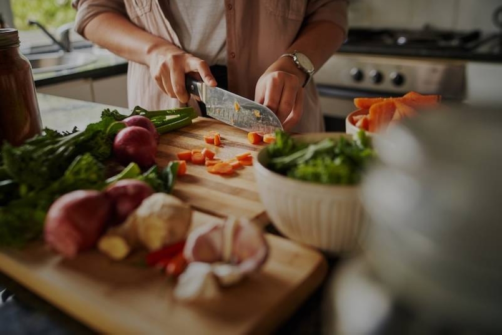 Más de 23 mil hogares dicen que no cocinan, compran comida exclusivamente, la pueden pasar comprando o la pide a domicilio.,image_description:Closeup of young female hands chopping fresh vegetables on chopping board while in modern kitchen  preparing a healthy meal to boost immune system and fight off coronavirus