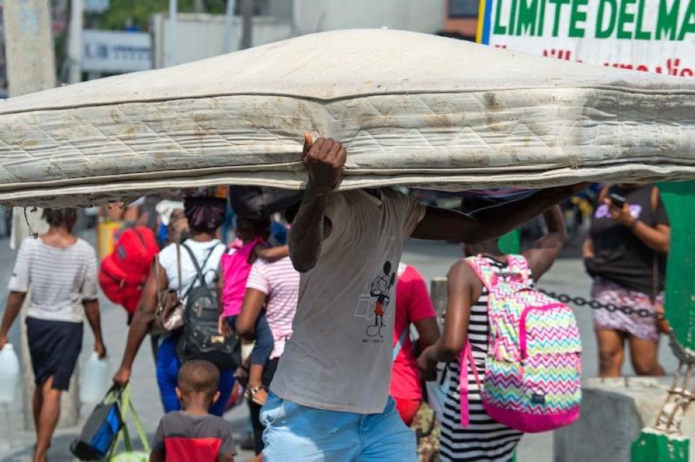 Un hombre lleva un colchón mientras los residentes evacuan su vecindario después de que bandas armadas infundieran terror en las áreas de Delmas 24 y Solino en Puerto Príncipe, la capital de Haití./AFP ,image_description: