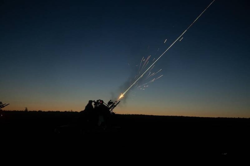 Soldados ucranianos disparan armas antiáreas contra aviones rusos.,image_description: