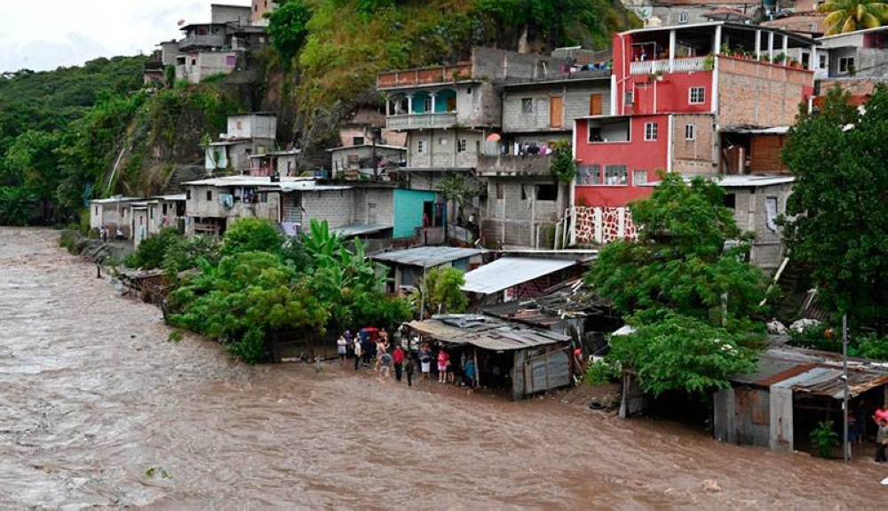 Un grupo de personas ven la crecida del río Choluteca en Honduras. / AFP,image_description: