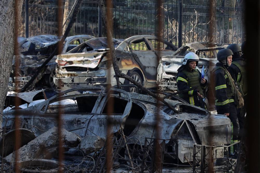 Rescatistas ucranianos se encuentran entre autos calcinados en el patio de un edificio residencial tras un ataque con misiles en Odesa el 18 de noviembre de 2024./Foto cortesía Oleksandr Gimanov AFP.,image_description: