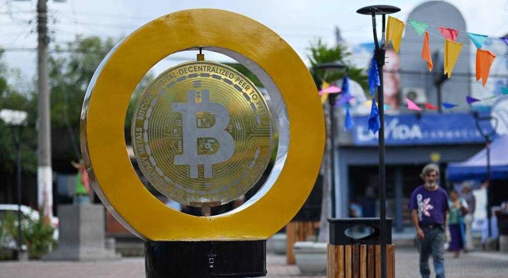 Un hombre pasa junto a un monumento a bitcoin en la Plaza Bitcoin en San Salvador el 4 de septiembre de 2024/ Foto AFP.,image_description: