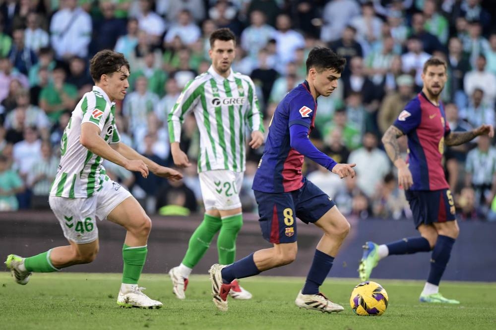 Pedri escapa de la marca de los jugadores del Betis. / AFP,image_description: