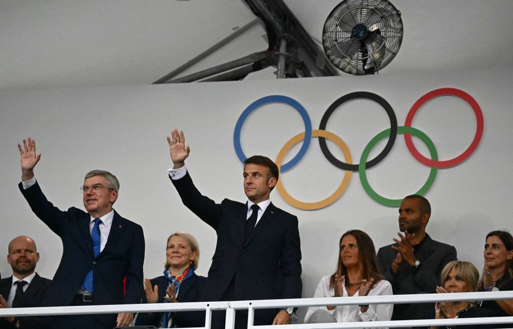 El presidente de Francia, Emmanuel Macron (R), y el presidente del Comité Olímpico Internacional (COI), Thomas Bach, saludan cuando llegan para asistir a la ceremonia de apertura de los Juegos Olímpicos de París 2024 en París el 26 de julio de 2024. (Foto de Loic VENANCE / POOL /AFP)