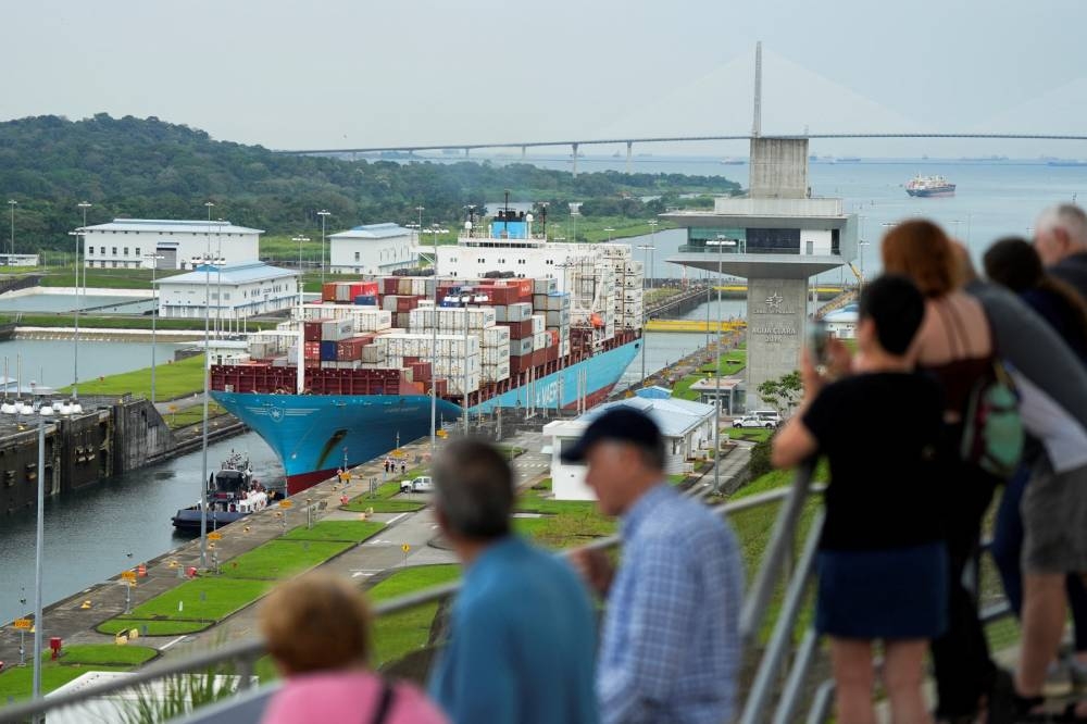 Los turistas observan el carguero danés Lars Maersk navegando por las esclusas de Agua Clara del Canal de Panamá en la ciudad de Colón, Panamá, el 28 de diciembre de 2024. / AFP.,image_description: