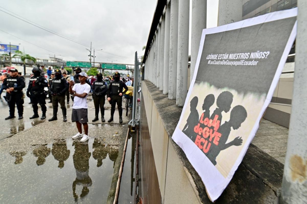 Agentes de policía hacen guardia durante una manifestación contra la desaparición de cuatro menores que desaparecieron durante una operación militar, frente al juzgado de Guayaquil, Ecuador, el 31 de diciembre de 2024, durante la audiencia de instrucción de cargos contra 16 militares presuntamente involucrados en la desaparición/ Marcos Pin AFP.,image_description: