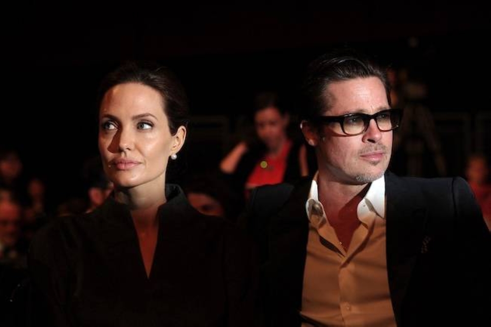 La actriz estadounidense  Angelina Jolie izq. y su entonces esposo, el actor estadounidense Brad Pitt, en una foto del 13 de junio de 2014. Los famosos actores Brad Pitt y Angelina Jolie firmaron un acuerdo de divorcio el 30 de diciembre de 2024, según la revista People, lo que marca un punto de inflexión en la saga legal de ocho años. / AFP,image_description: