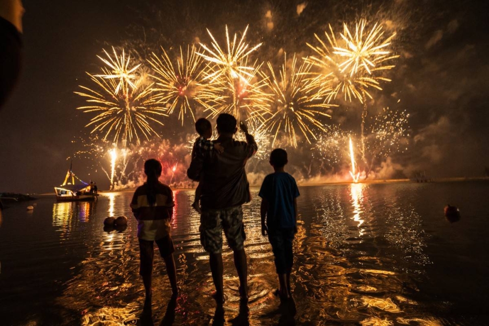 Los residentes locales observan los fuegos artificiales mientras celebran el Año Nuevo en la playa Ancol en Yakarta el 1 de enero de 2025. /AFP,image_description: