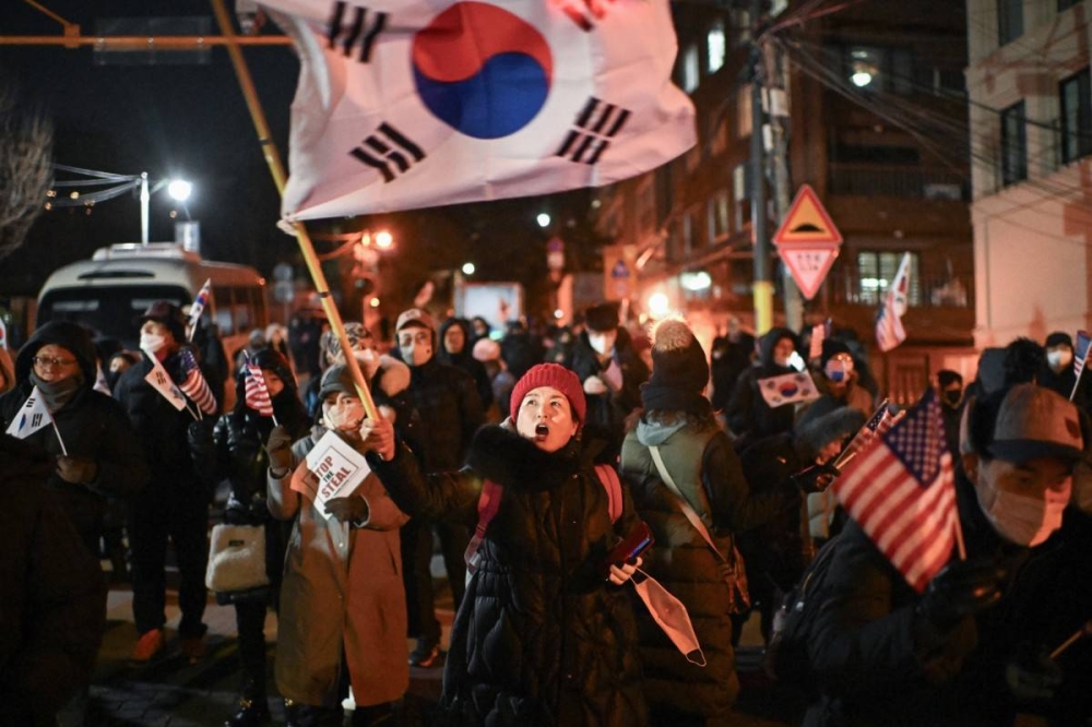 Una mujer ondea la bandera de Corea del Sur durante una manifestación en apoyo al presidente destituido de Corea del Sur, Yoon Suk Yeol, cerca de la residencia presidencial en Seúl el 2 de enero de 2025./AFP,image_description: