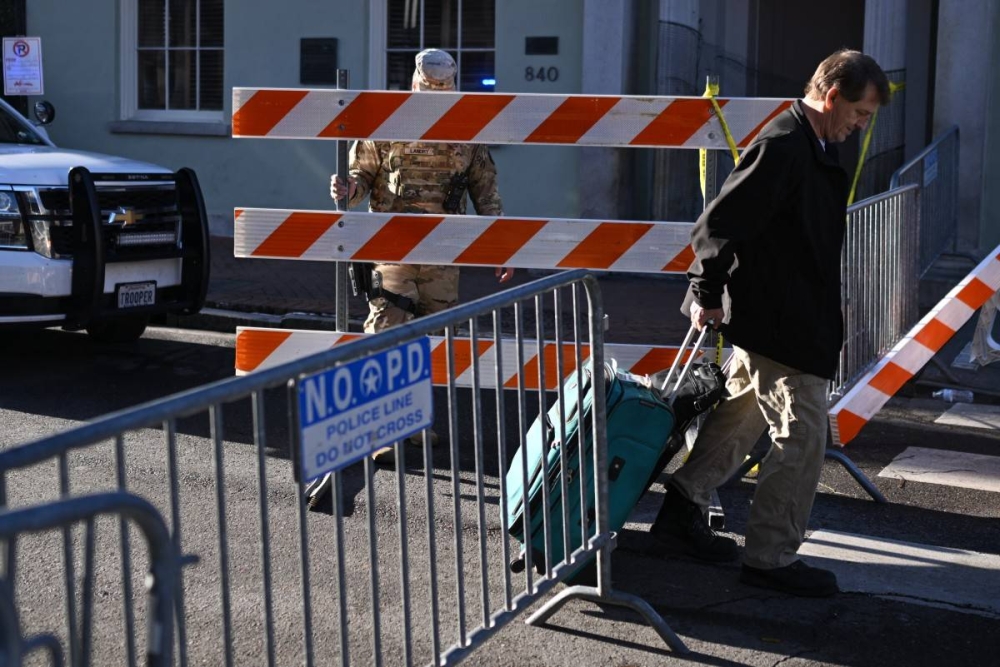 Un turista lleva su equipaje por una calle bloqueada en el Barrio Francés el 2 de enero de 2025 en Nueva Orleans, Luisiana, luego de un ataque terrorista en Bourbon Street el 1 de enero. /ANDREW CABALLEROREYNOLDS / AFP,image_description:Vehicle driven into New Years crowd in New Orleans