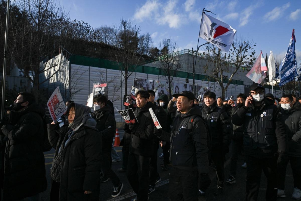 La gente grita consignas mientras lleva pancartas y ondea banderas durante una manifestación contra el presidente destituido de Corea del Sur, Yoon Suk Yeol, en Seúl el 3 de enero de 2025. Philip FONG / AFP,image_description: