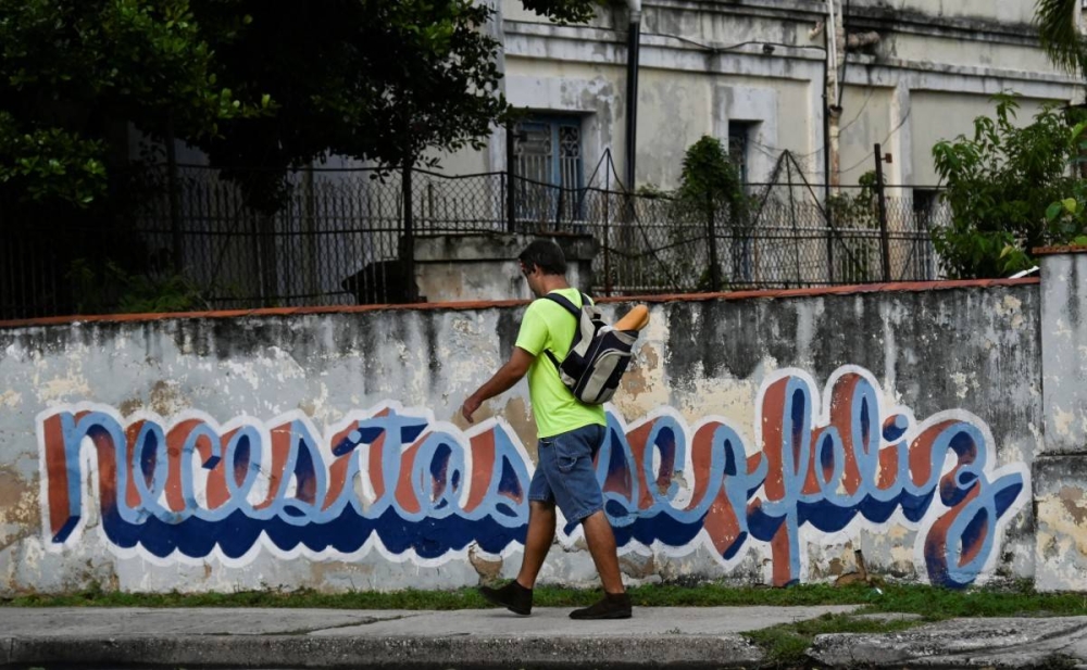 La icónica frase figura entre murales y grafitis comunes como un clamor del pueblo isleño. Photo by YAMIL LAGE / AFP,image_description: