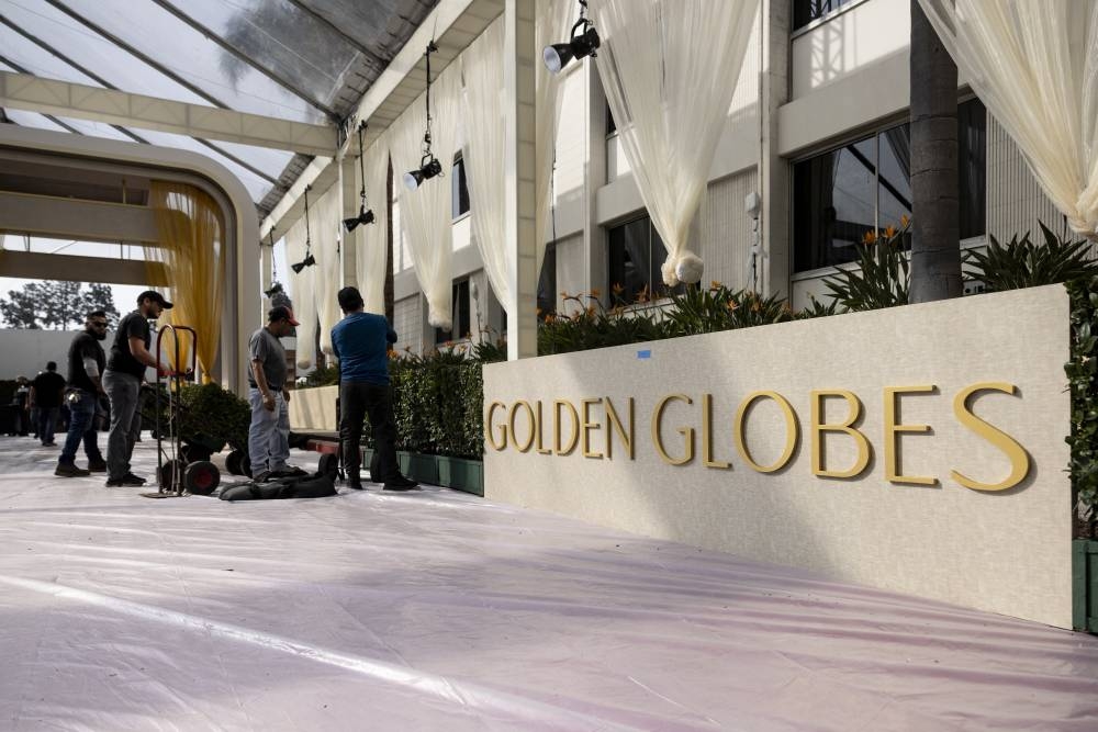 Los trabajadores colocan setos junto a la alfombra roja mientras los técnicos y trabajadores agregan los últimos toques de los Globos de Oro en Beverly Hilton en Beverly Hills, California. /AFP,image_description: