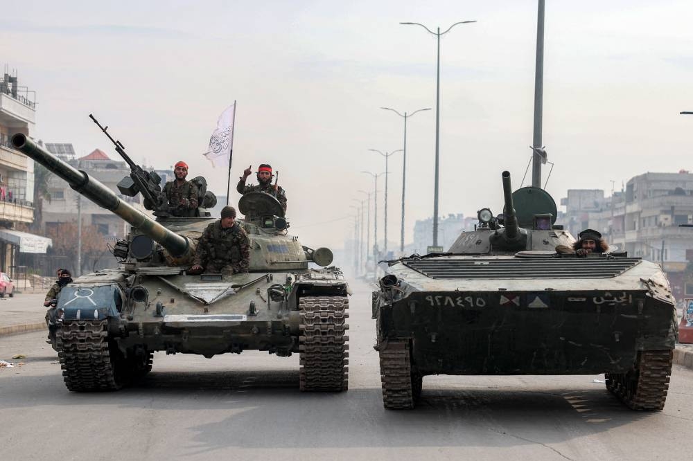 Combatientes leales al gobierno interino sirio viajan a bordo de un tanque de batalla principal y de un vehículo de combate de infantería. /AFP,image_description: