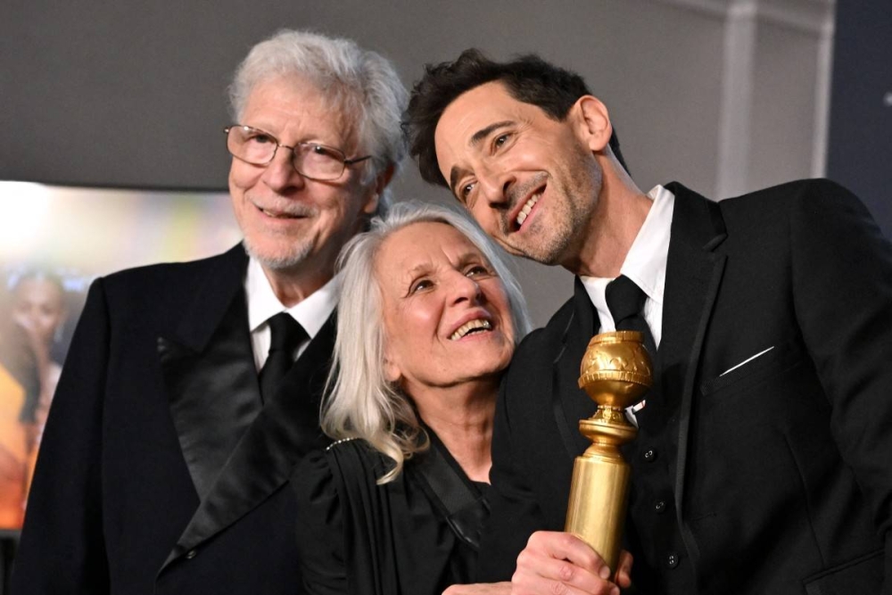 El actor estadounidense Adrien Brody, de 51 años, fue el mejor actor de un película drama por The Brutalist, acompañado de sus padres Sylvia Plachy y  Elliot Brody. Photo by Robyn BECK / AFP,image_description:82nd Golden Globe Awards ceremony  Press Room