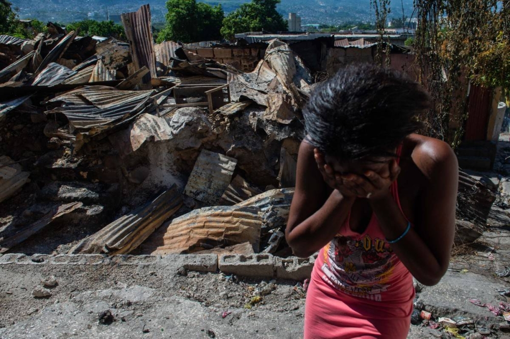  Una mujer llora afuera de su casa luego de que bandas armadas le prendieran fuego en el barrio de Post Marchand en Puerto Príncipe el 17 de diciembre de 2024. /AFP,image_description: