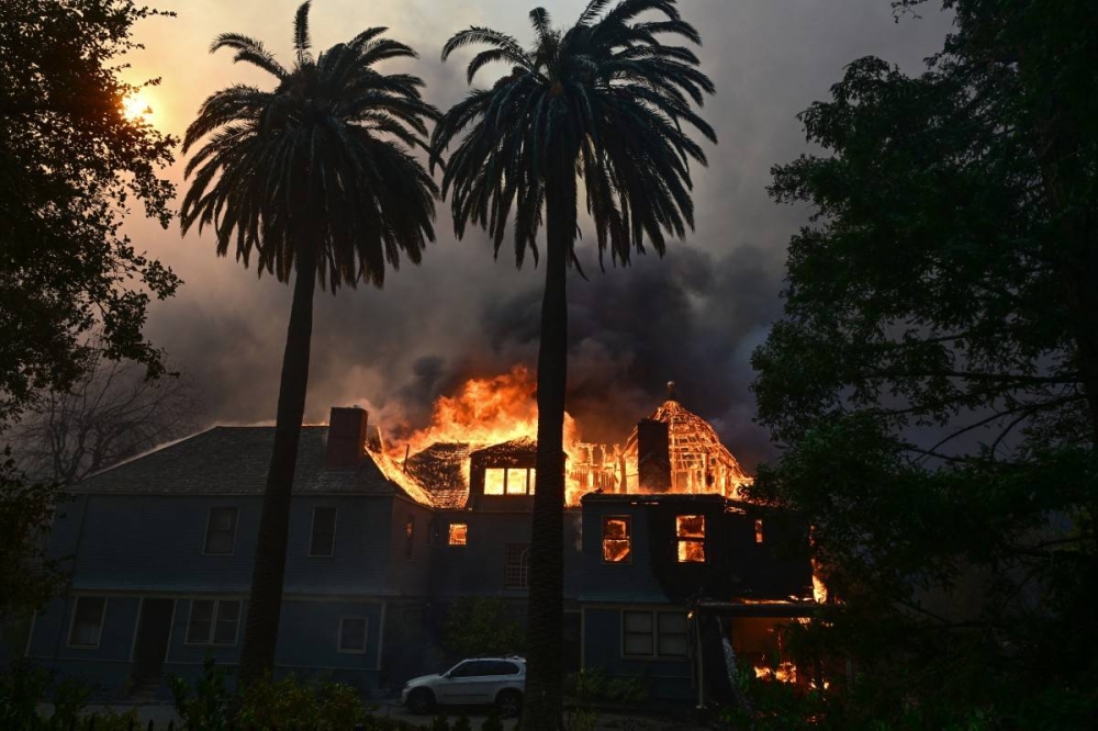 Una casa arde durante el incendio Eaton en Altadena, California, el 8 de enero de 2025. Los devastadores incendios forestales alrededor de Los Ángeles han matado al menos a dos personas, dijeron funcionarios el 8 de enero, mientras terribles llamas arrasaban calles enteras, incendiando automóviles y casas en minutos/Foto Robyn Beck AFP.,image_description: