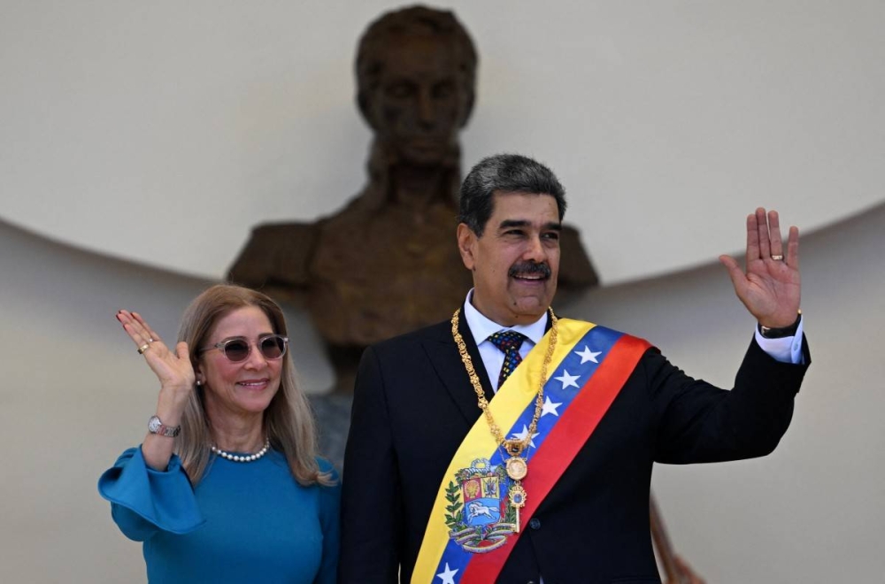 Venezuelas President Nicolas Maduro and his wife Cilia Flores wave to supporters as they leave the Capitolio home of the National Assembly after taking the oath during the presidential inauguration in Caracas on January 10, 2025. Maduro, in power since 2013, took the oath of office for a third term despite a global outcry that brought thousands out in protest on the ceremonys eve. Photo by Juan BARRETO / AFP,image_description: